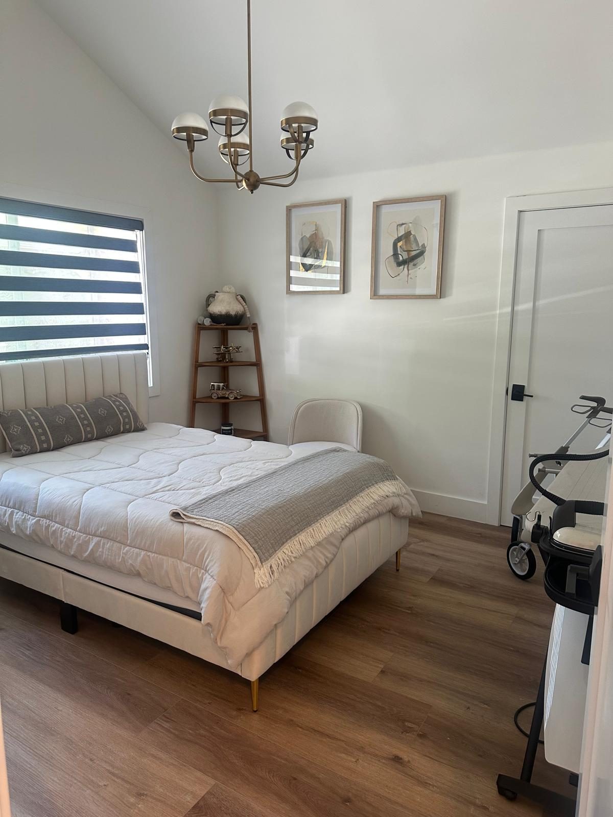 Resident bedroom with upholstered bed and chandelier at Monogram Villa in Sherman Oaks